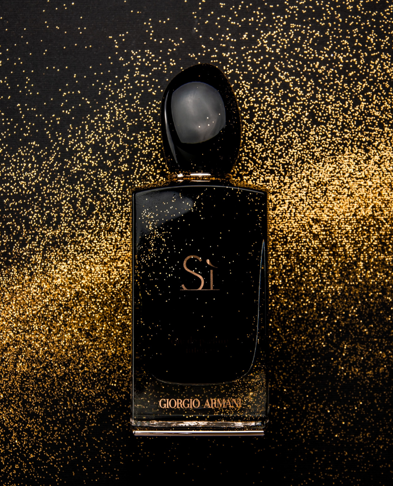 a image of a fragrance bottle with a background of gold specks | What's the Difference Between Eau de Toilette and Eau de Perfume