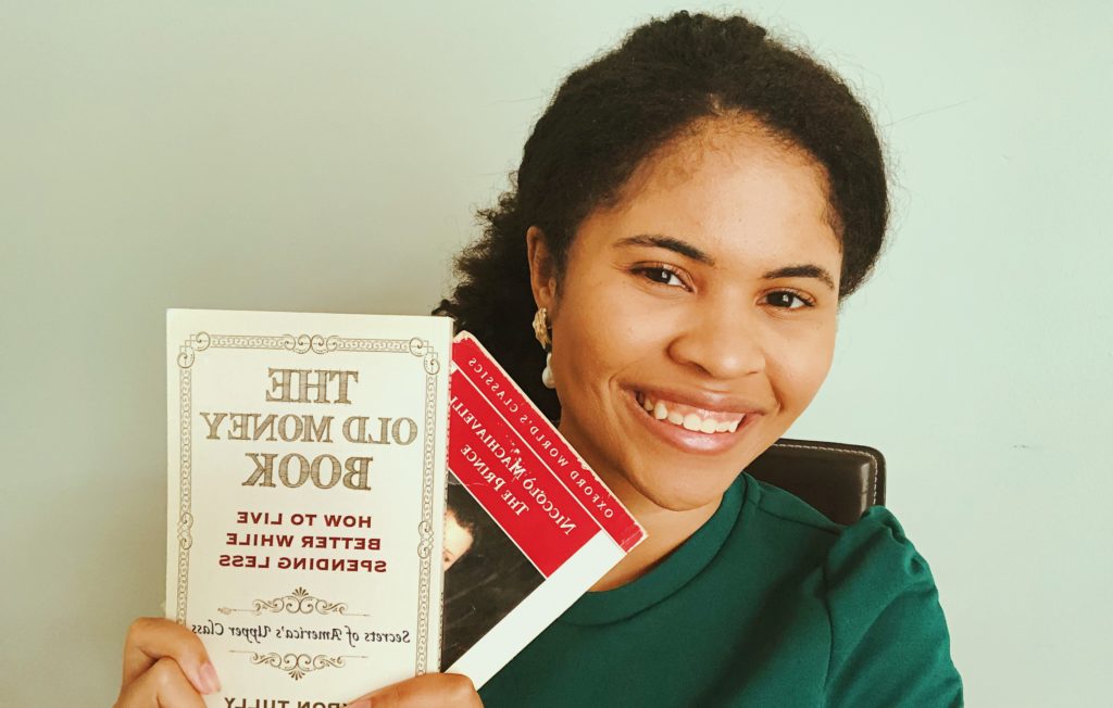 a photo of a black girl smiling with two books in her hand